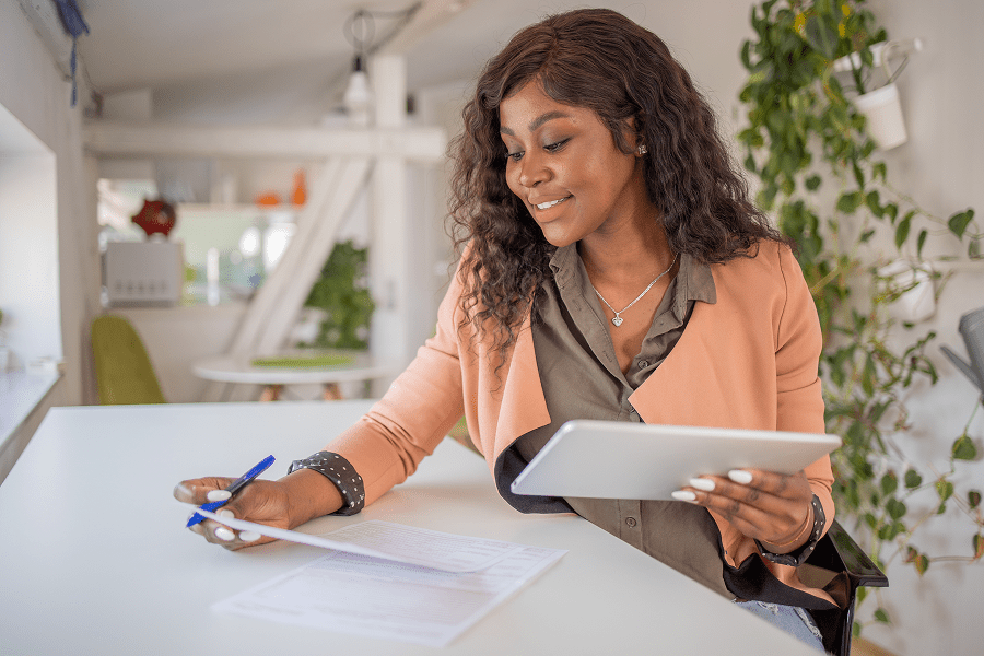 Woman working with tablet and paper documents.